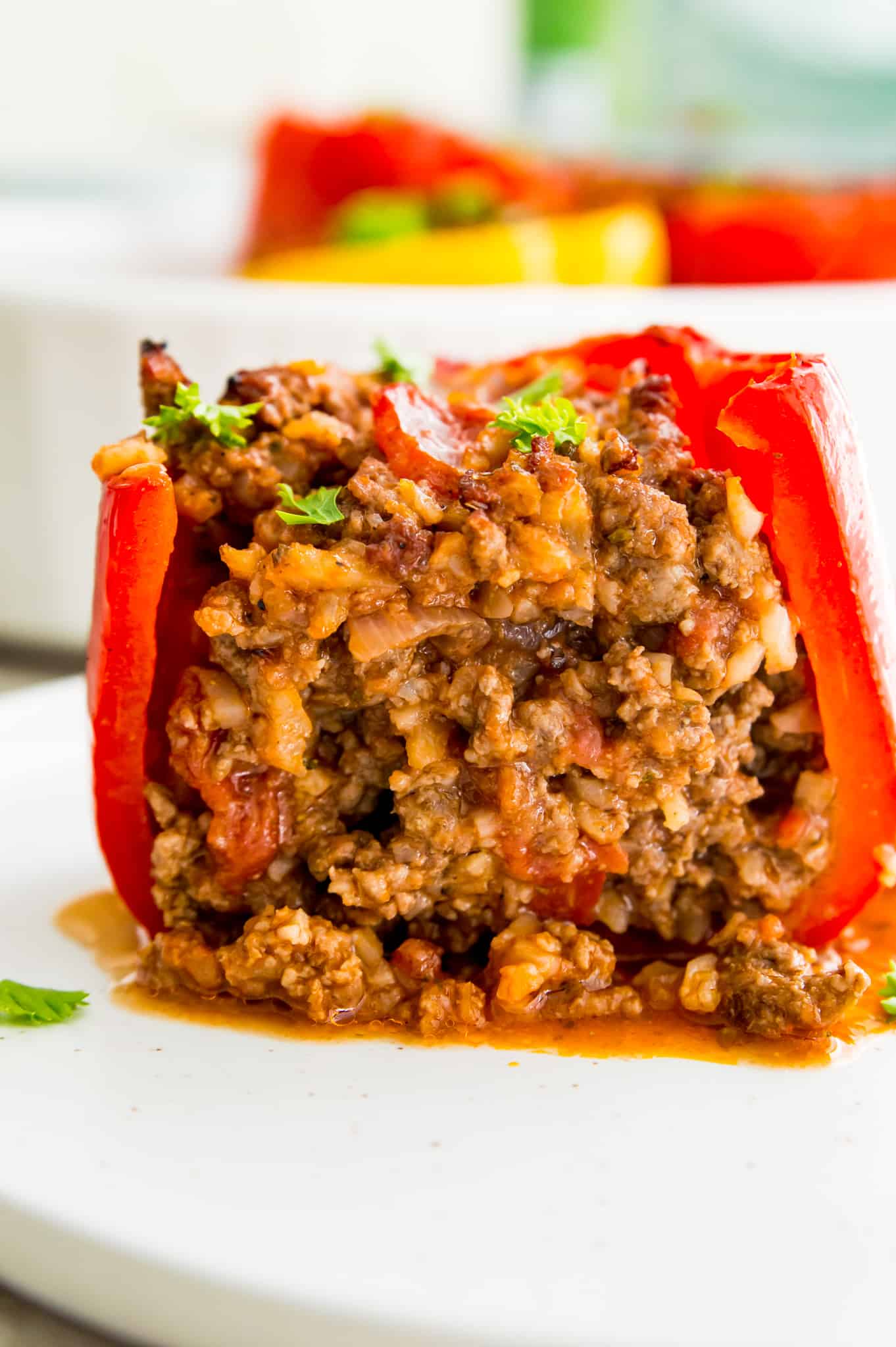 A stuffed red pepper cut in half so you can see the ground beef filling in it.