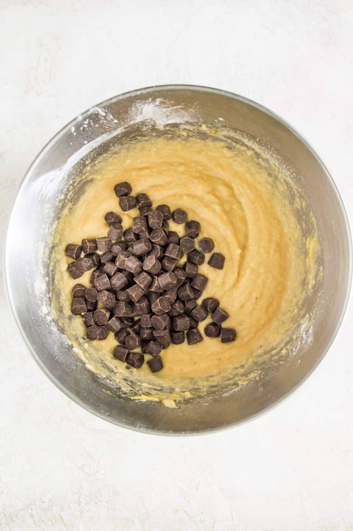 A metal bowl with batter in it topped with chocolate chips.