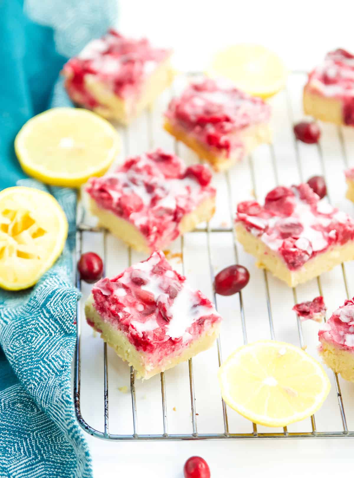 Many gluten free lemon bars with cranberry on a wire rack