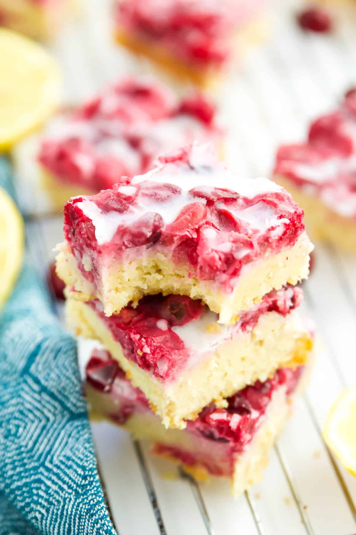 A stack of three gluten free lemon bars with cranberry and the top bar has a bite out of it.