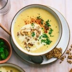 A bowl of creamy soup topped with fresh parsley and crushed crackers.