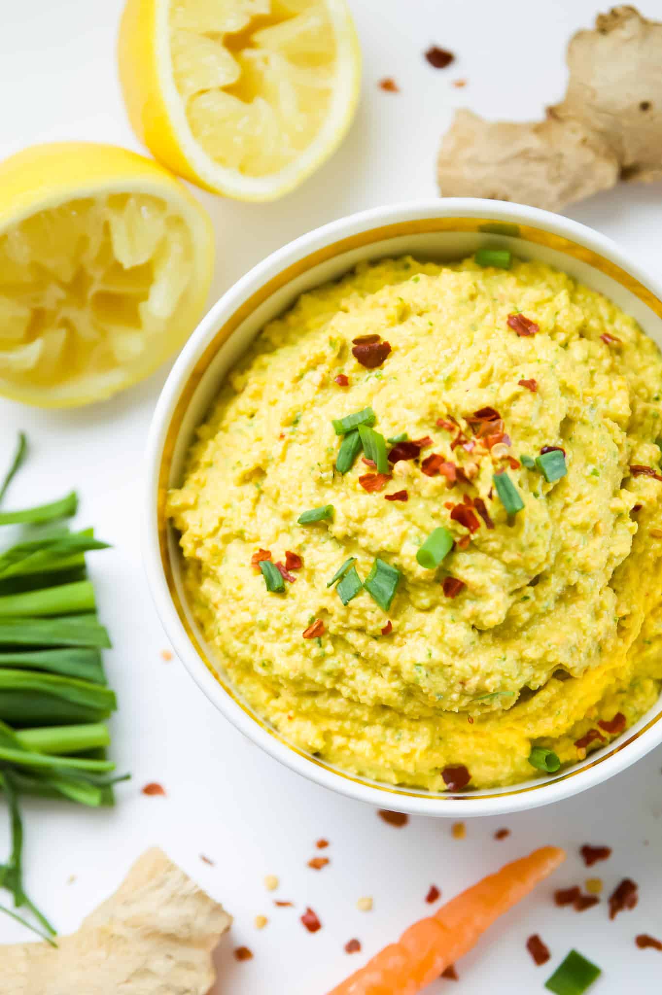 A bowl full of paleo carrot dip with chilis garnished with sliced green onions.