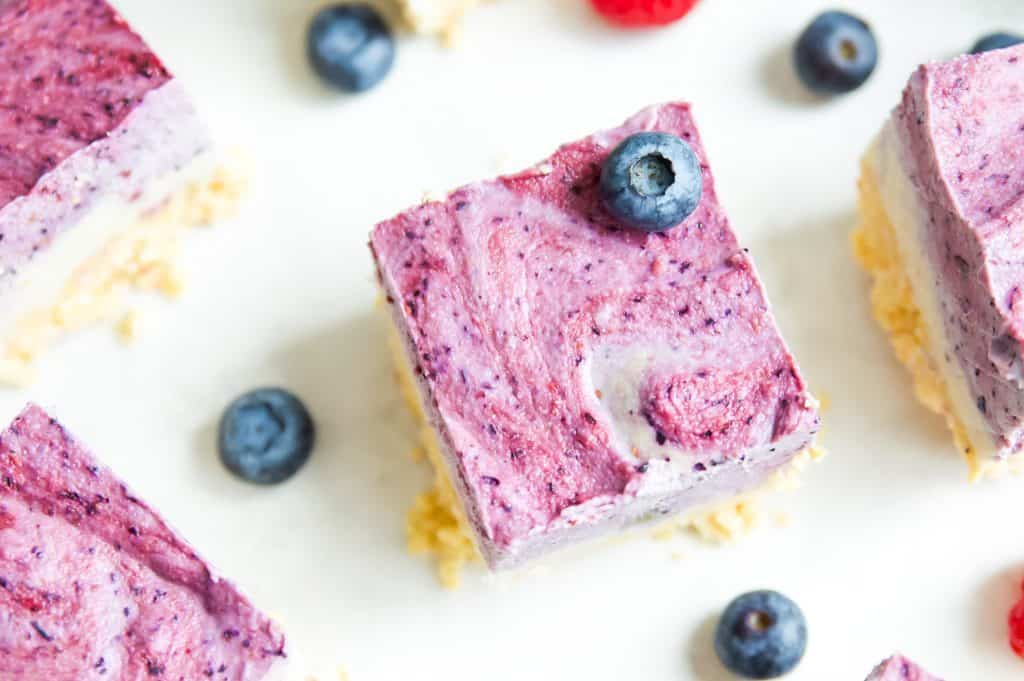 Overhead shot of paleo ice cream bars with berries and blueberries scattered around the bars. 