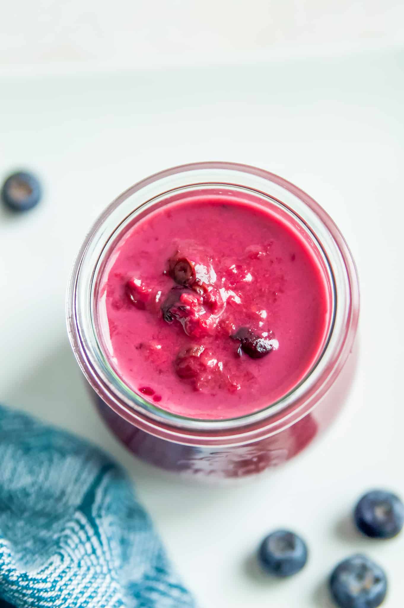 A jar of raspberry blueberry sauce with a spoon in it. 