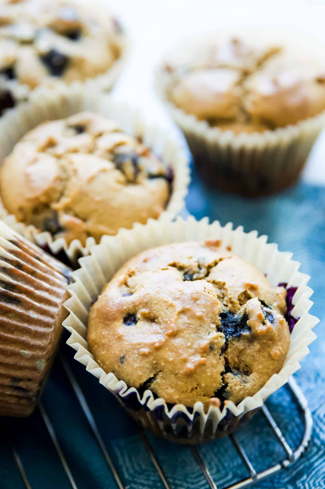 A gluten free blueberry muffin in a parchment paper muffin cup. 