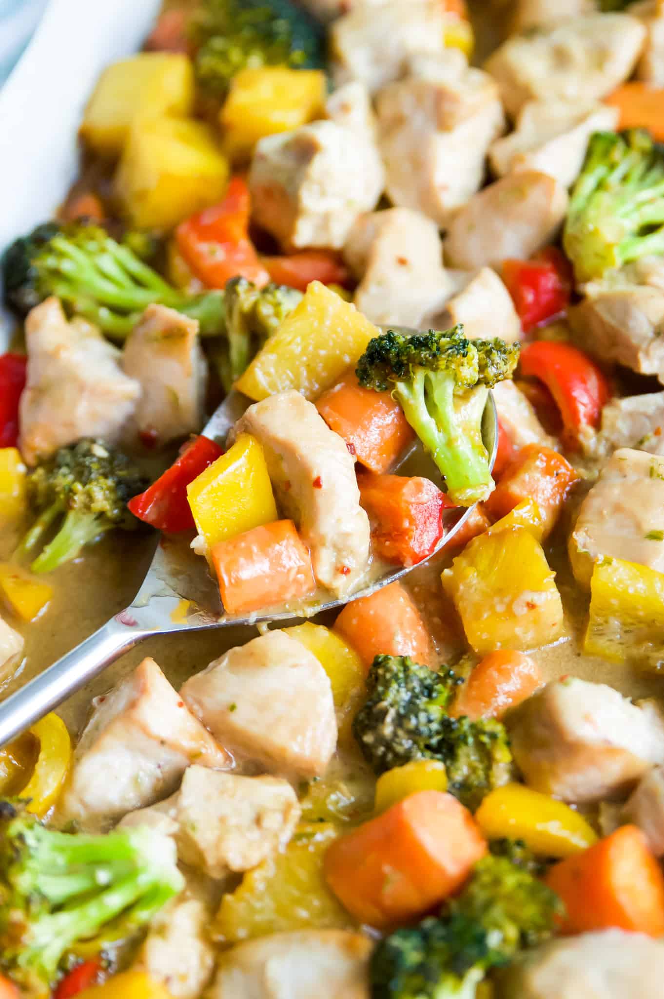 A serving spoon full of teriyaki chicken stir fry and vegetables. 