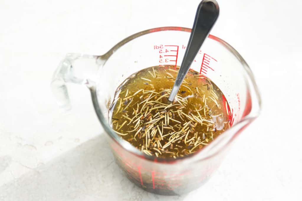 A glass measuring cup filled with marinade and a spoon.