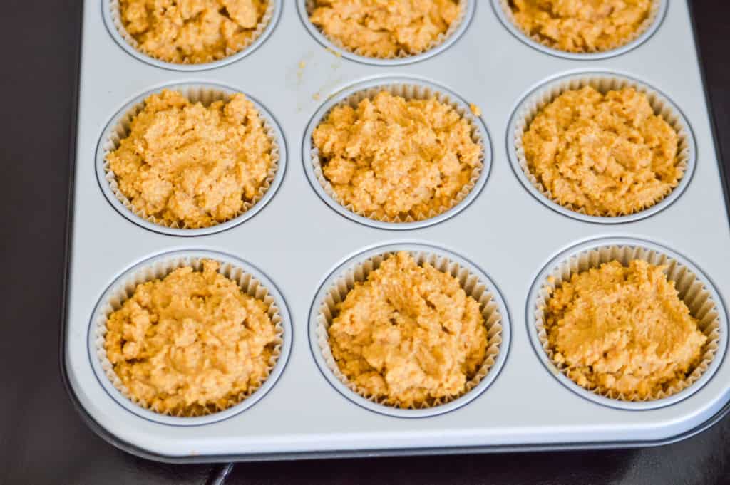 a muffin tray filled with batter to make gluten free pumpkin muffins with chocolate 