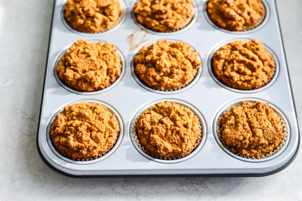a muffin tray filled with baked gluten free pumpkin muffins 