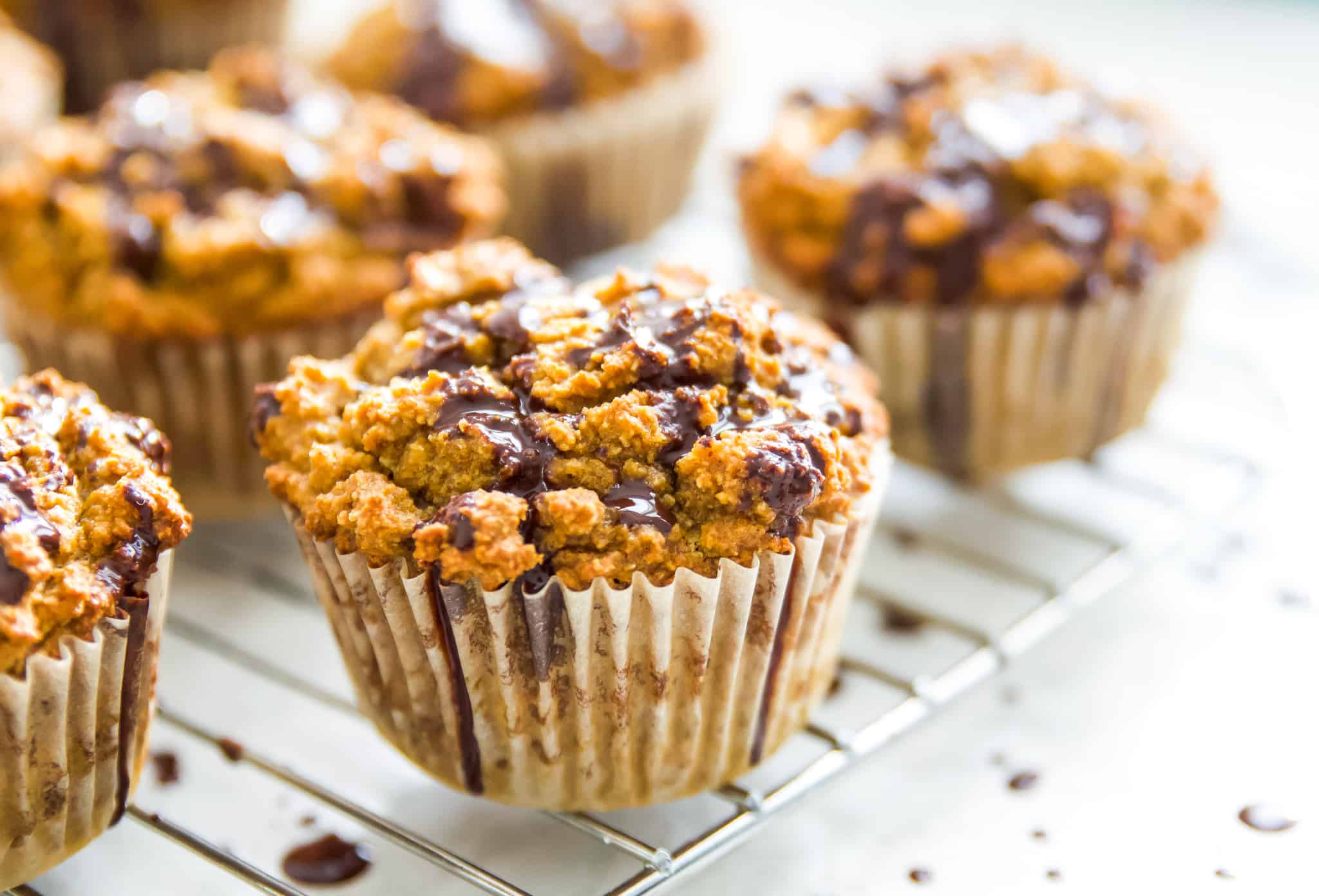 Gluten free pumpkin muffins with chocolate drizzled over them on a baking rack. 