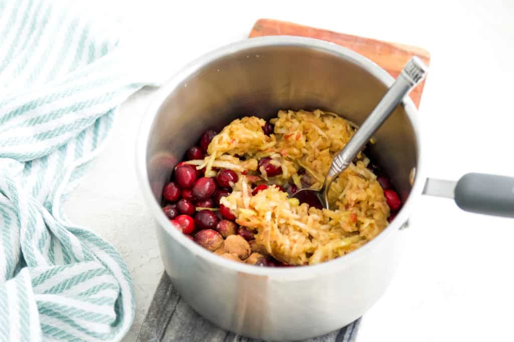 A pot filled with shredded apple and cranberries. 