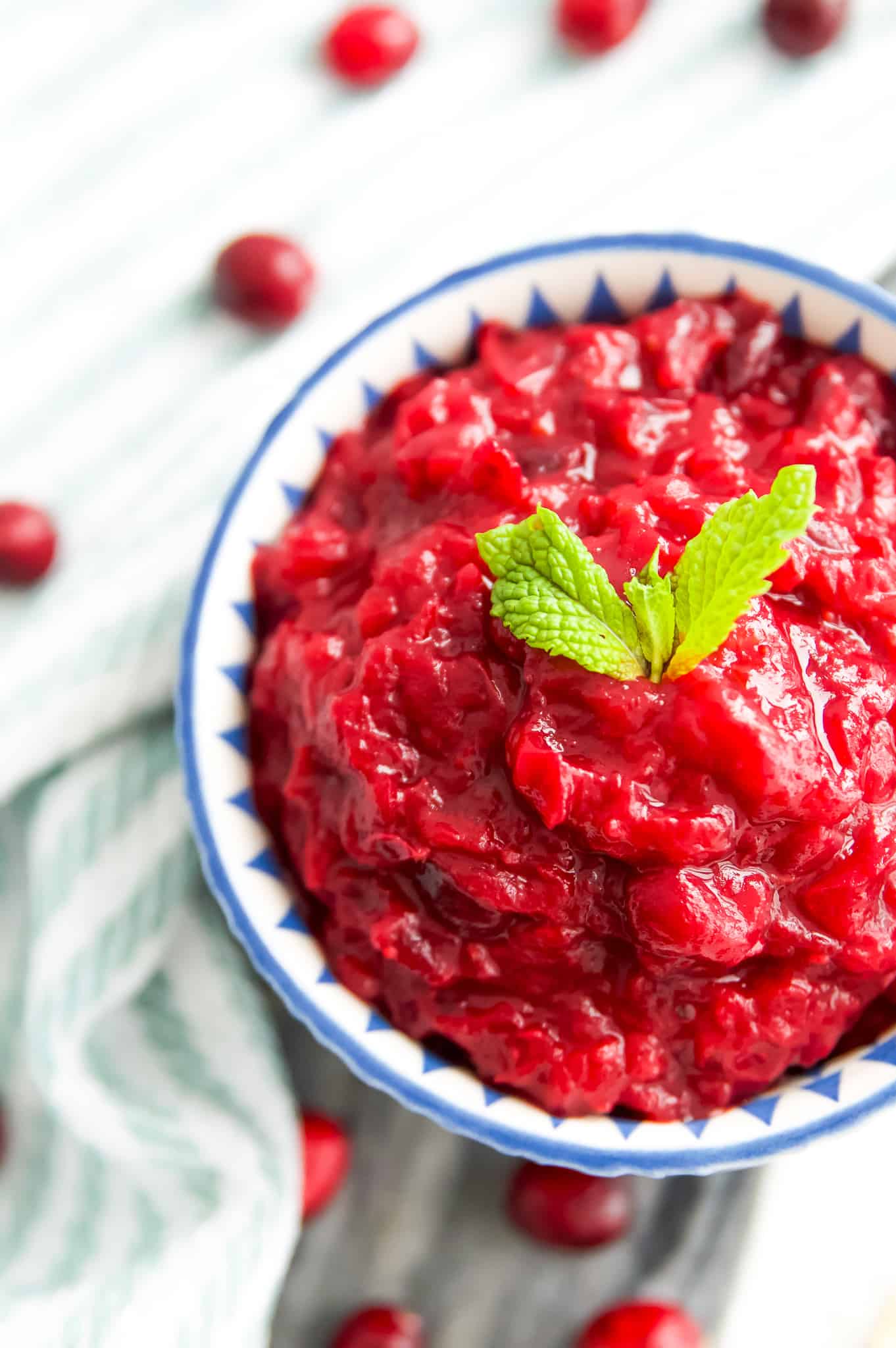 A bowl of sugar free cranberry sauce with fresh mint leaves on top for garnish.