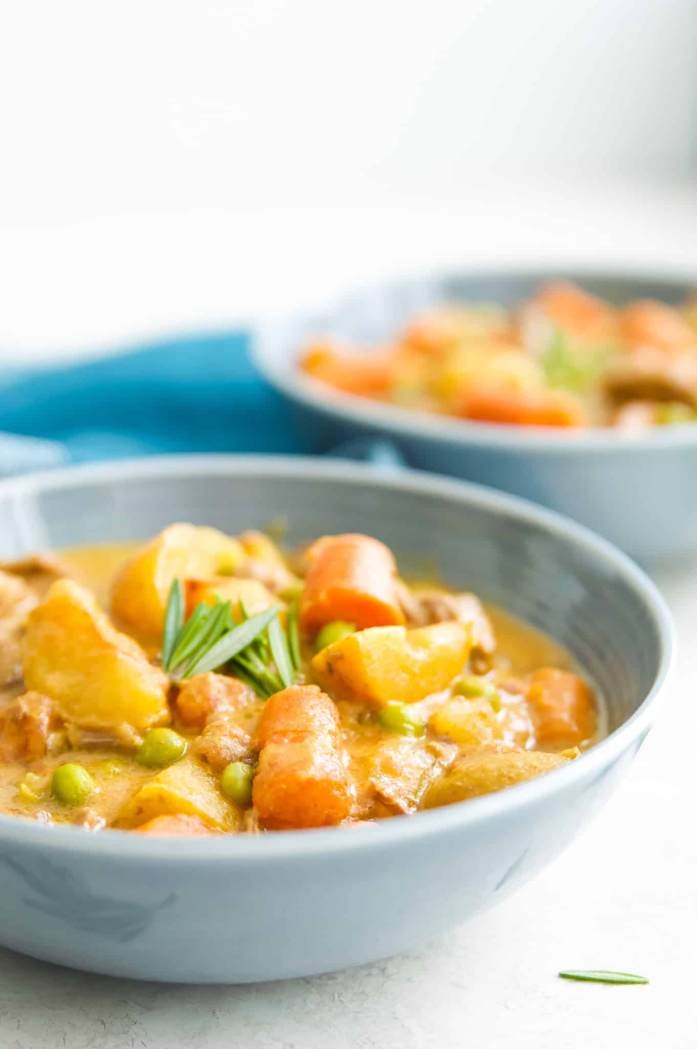 A bowl of beef curry stew garnished with fresh rosemary.