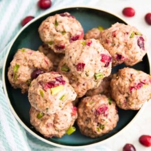 A bowl full of cranberry turkey meatballs, with fresh cranberries spread out around the bowl.
