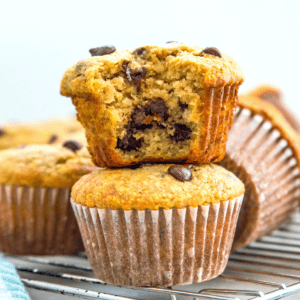 A stack of two paleo banana muffins with chocolate, and the top one has a bite out of it.