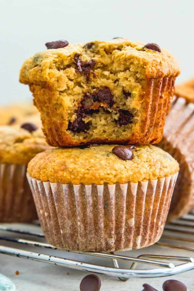 A stack of two banana chocolate chip muffins and the top muffin has a bite out of it.