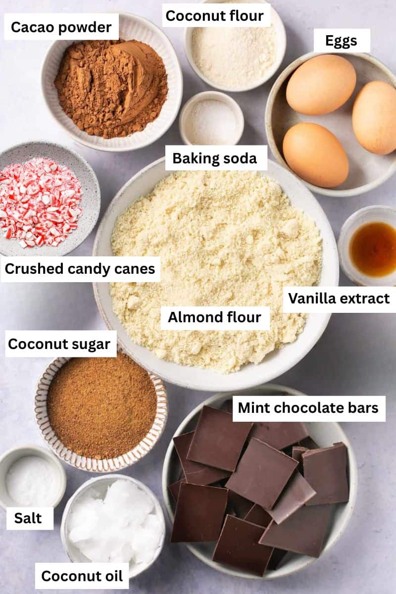 Ingredients for making mint brownies separated into bowls including flour, eggs, sugar, coconut oil, crushed candy canes vanilla extract.