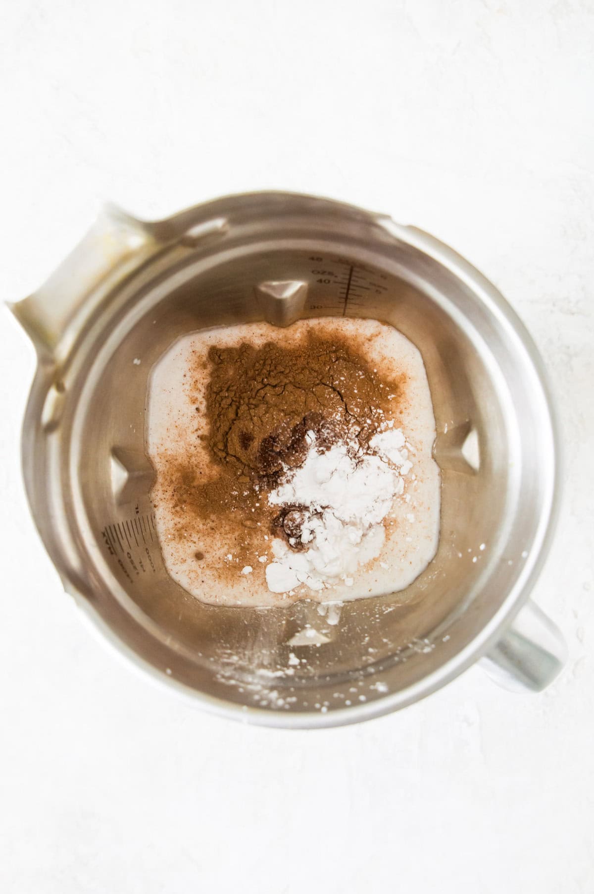 A blender with milk and spices in it.