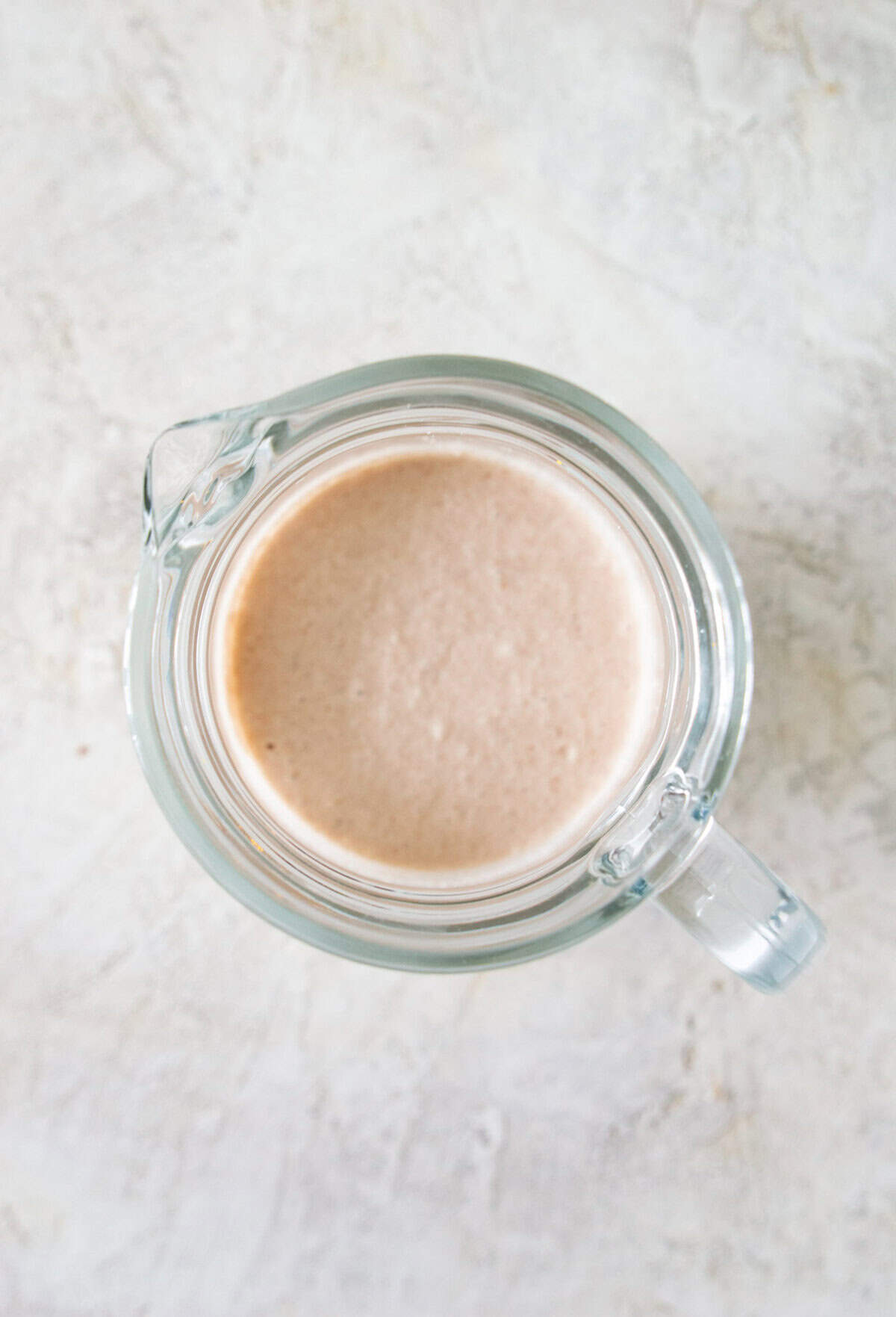 A glass pitcher with a thick, white creamy liquid in it.