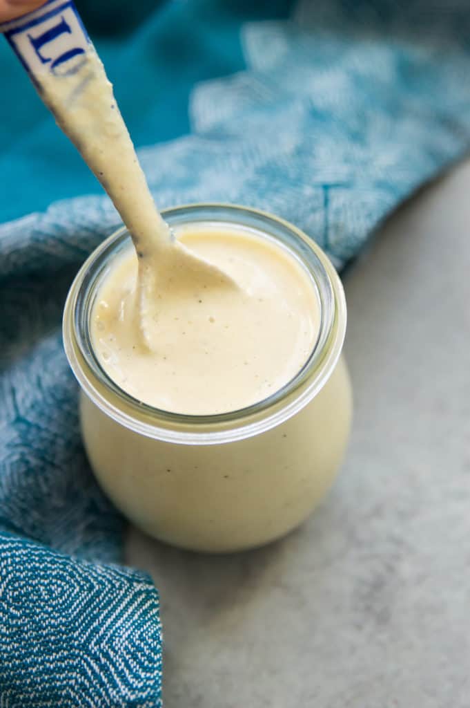 A jar of dairy free Alfredo sauce with a spoon in it