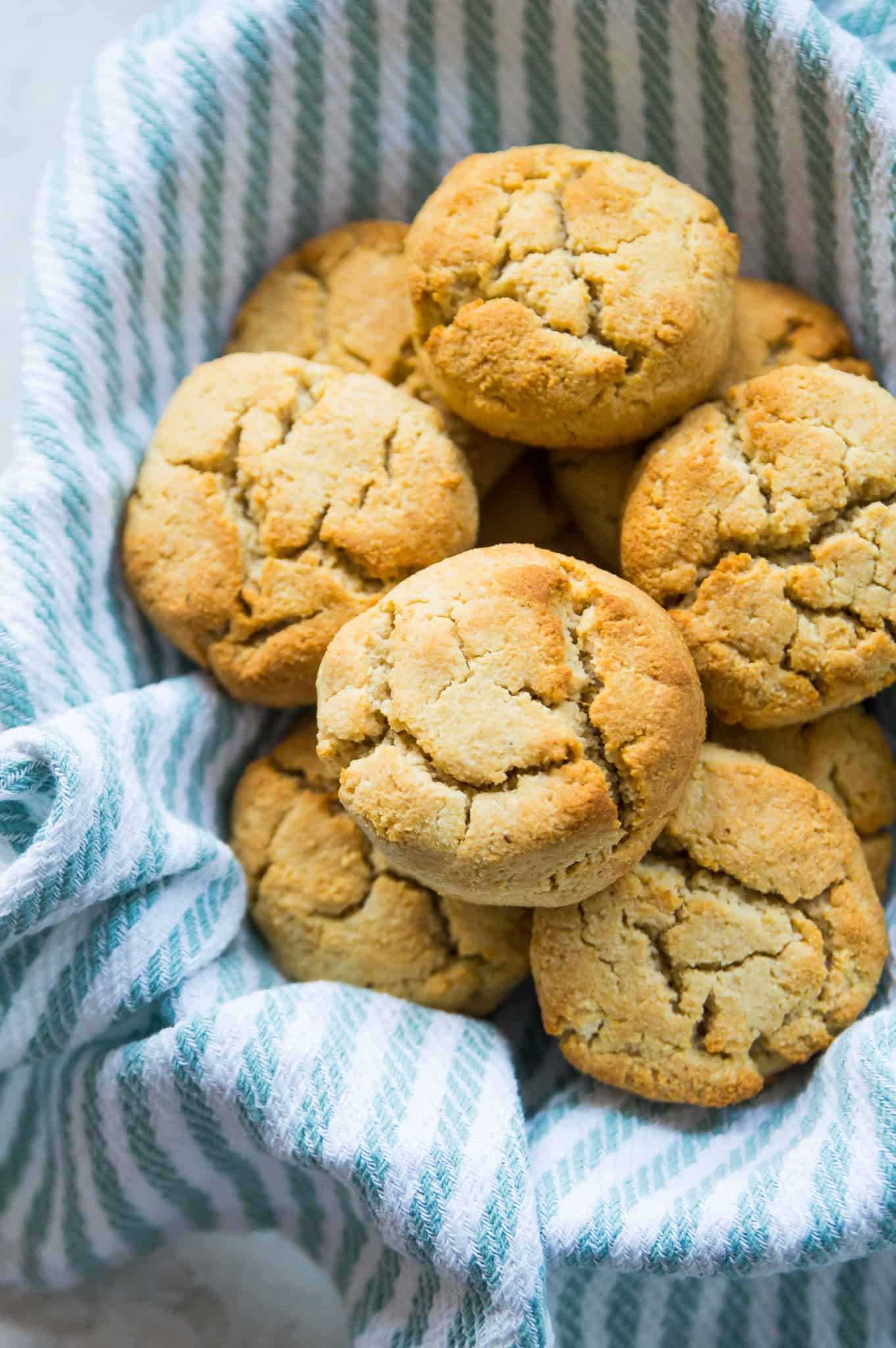 A basket full of almond flour biscuits lined with a tea towel.