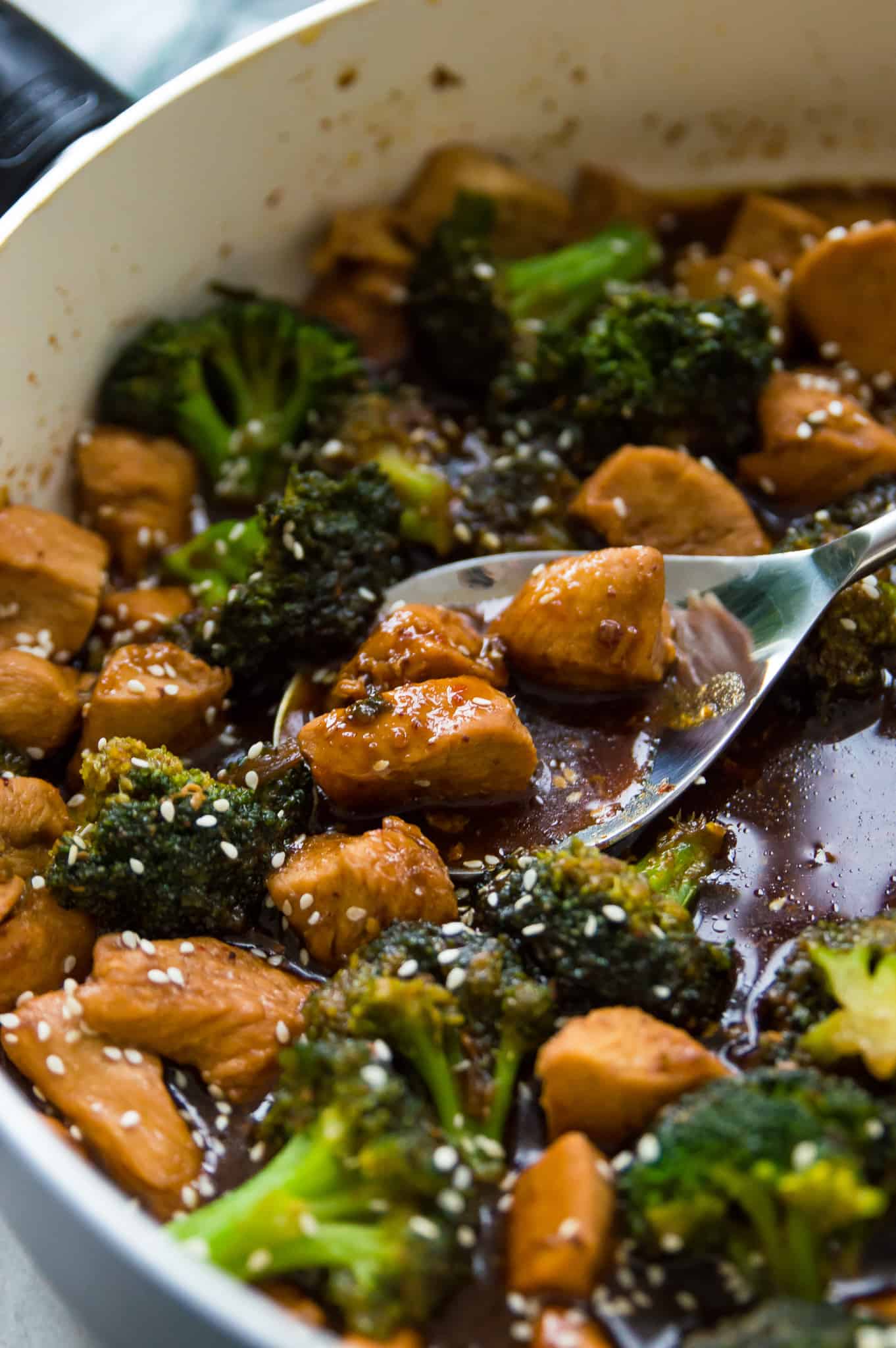 A pan filled with Whole30 teriyaki chicken and broccoli with a serving spoon in it.