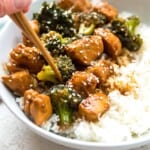 A bowl of Whole30 teriyaki chicken and broccoli with chopsticks in it.