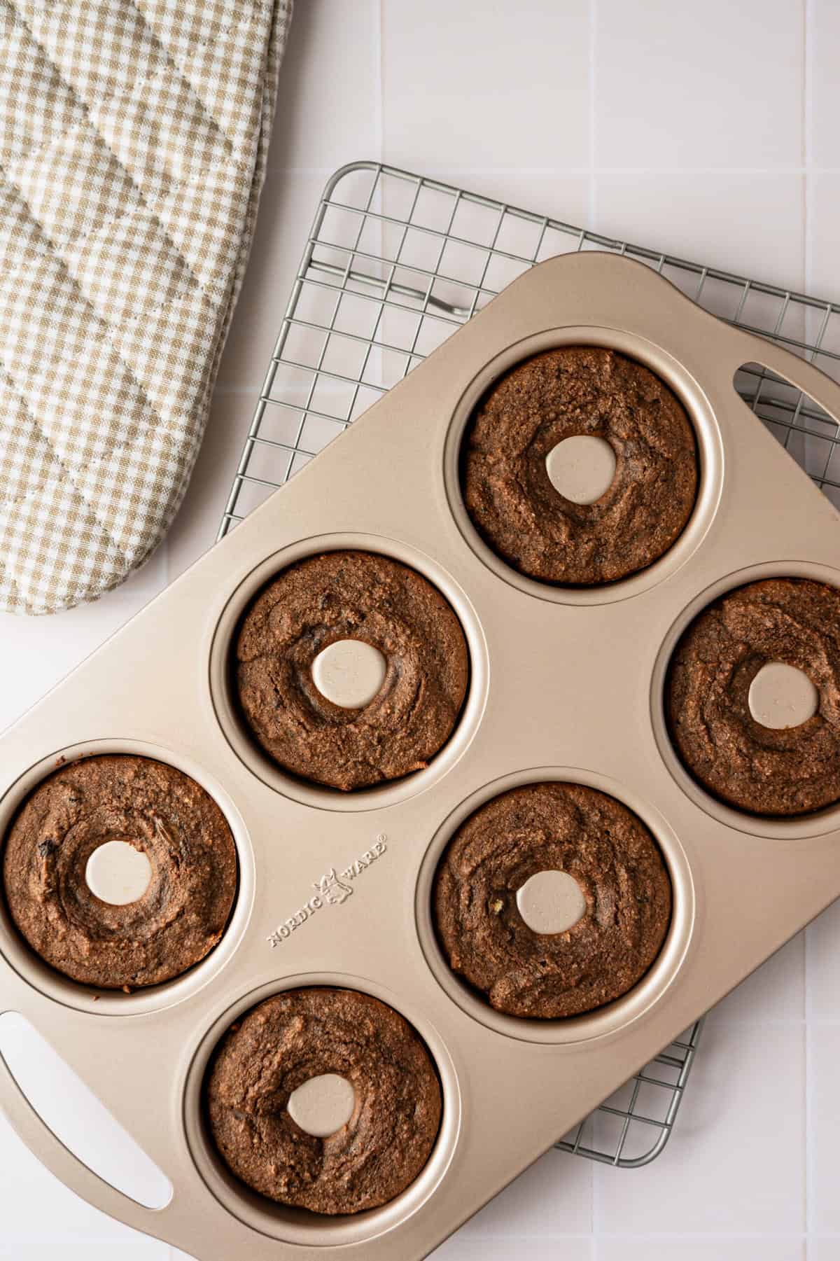 A donut mold filled with baked chocolate donuts.