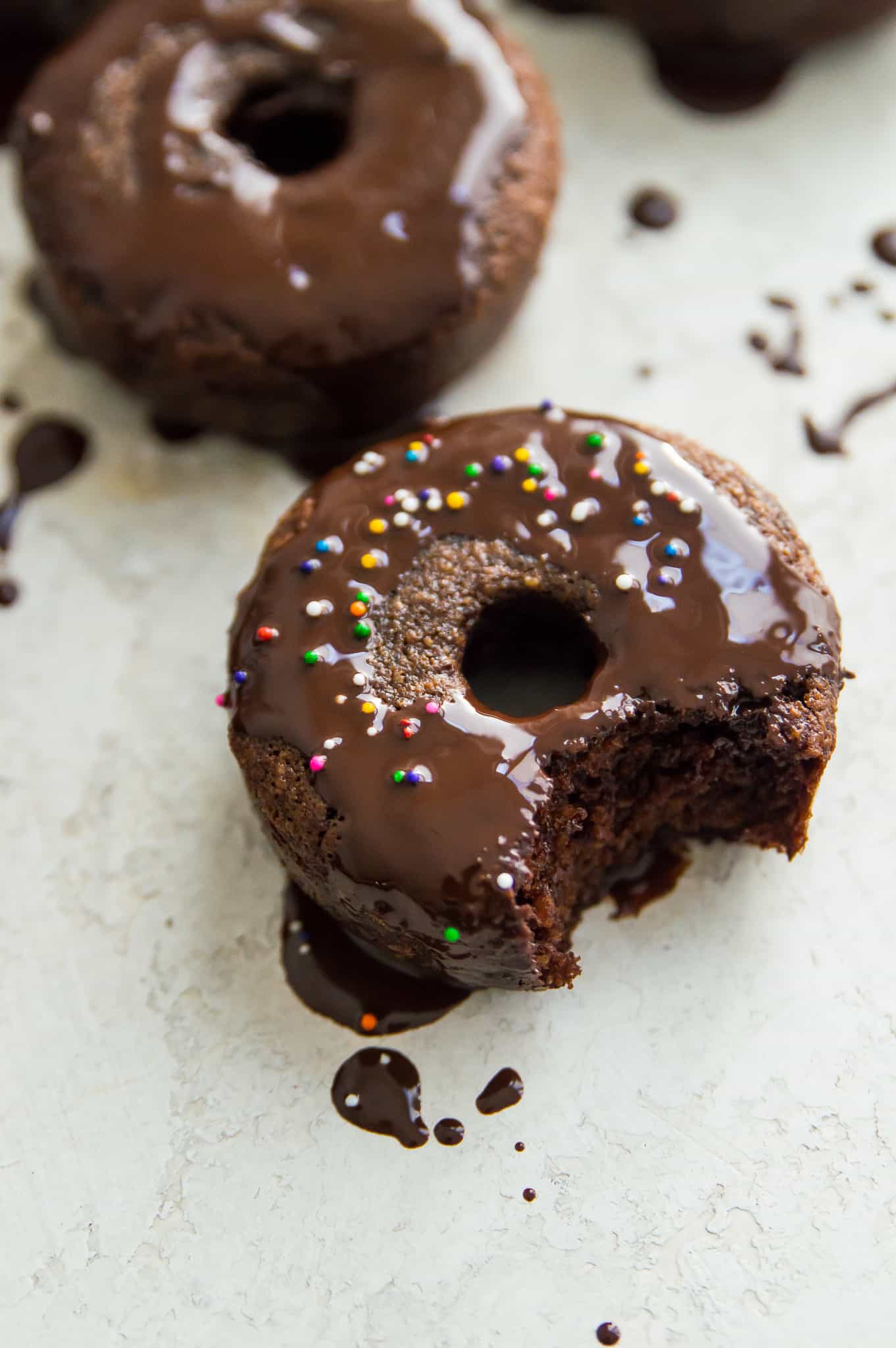 A dairy free chocolate donut with icing and sprinkles on it.