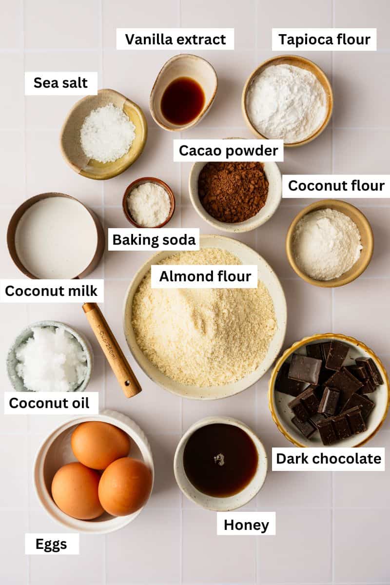 The ingredients needed for making chocolate donuts separated into bowls including flour, honey, coconut oil, cacao powder and baking soda.