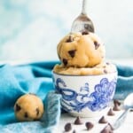 A bowl of edible gluten free chocolate chip cookie dough with a spoon in it.