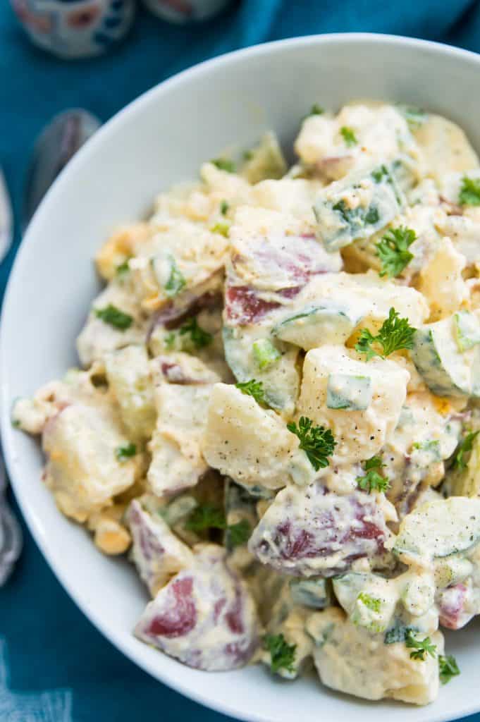 A bowl of potato salad garnished with parsley 
