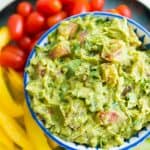 A bowl of guacamole surrounded by vegetables