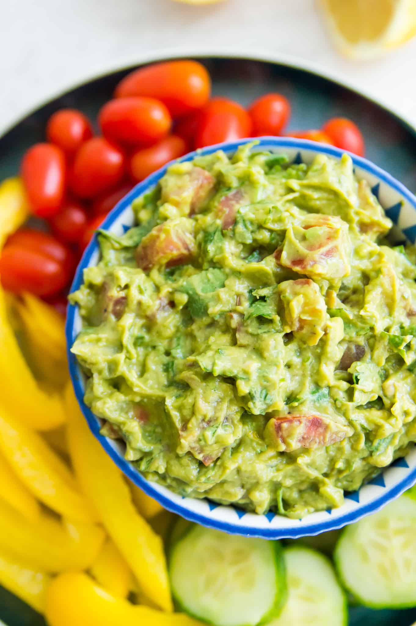 A bowl of guacamole surrounded by raw veggies.