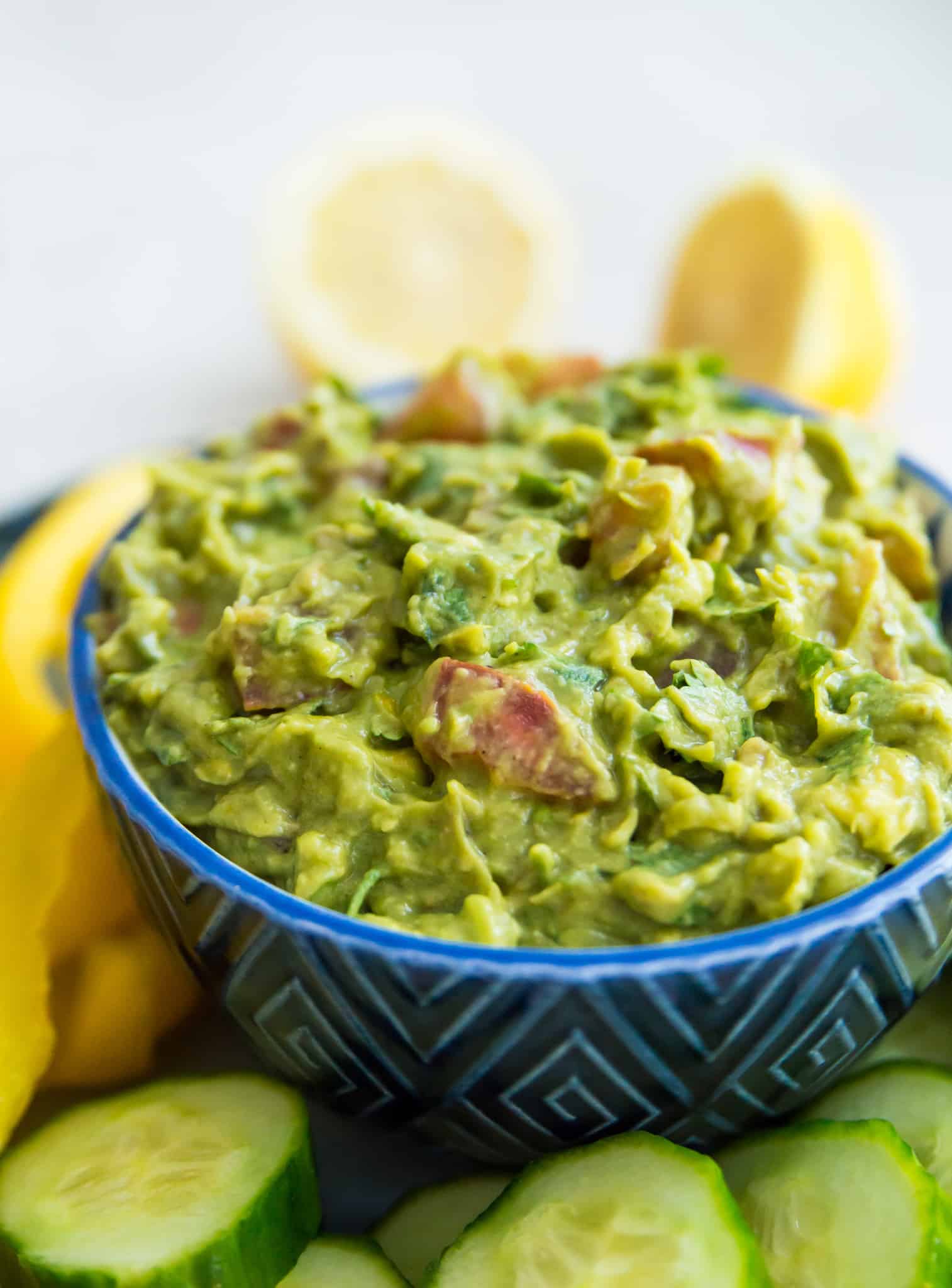 A bowl of guacamole on a tray with vegetables. 