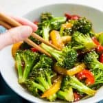 A bowl of teriyaki broccoli and peppers with chopsticks