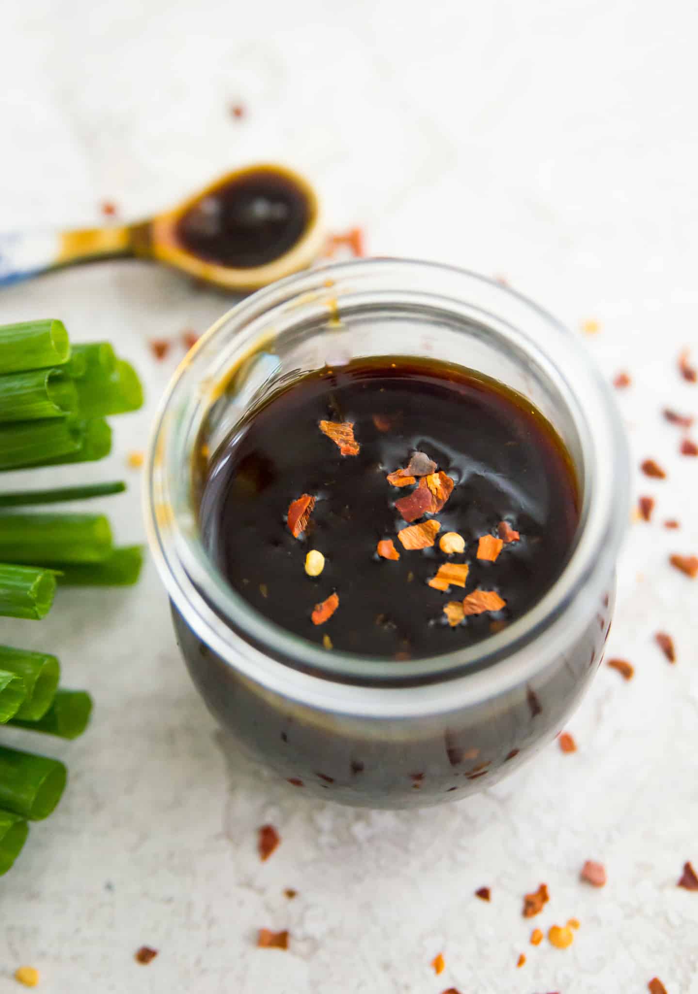 A jar of teriyaki sauce with chili flakes on top.