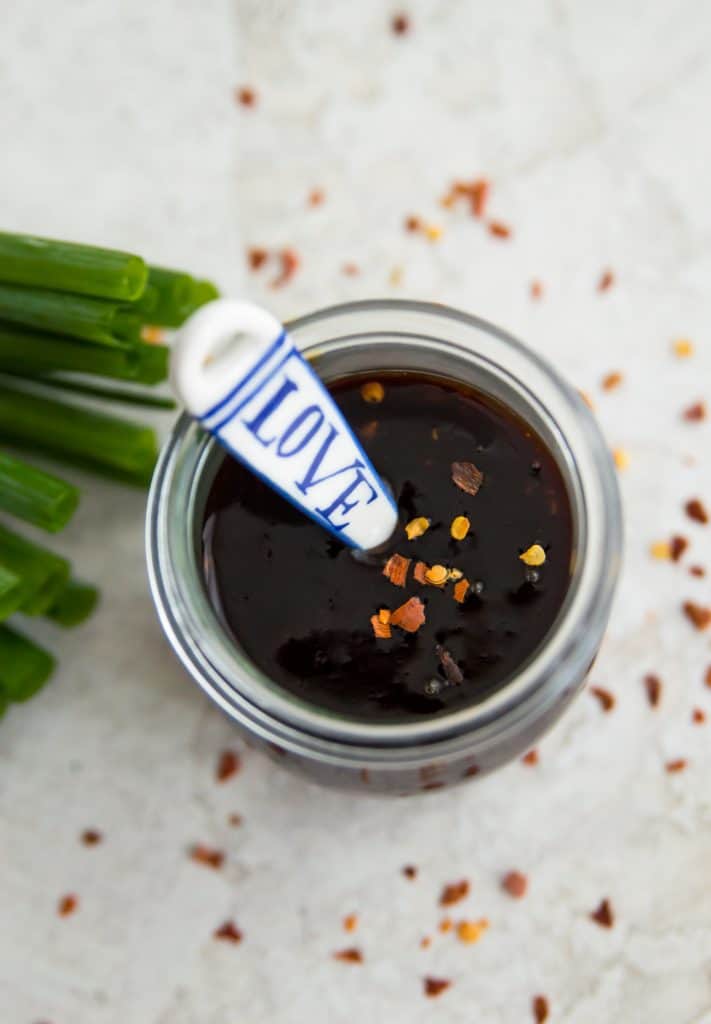A jar of teriyaki sauce with a spoon in it 
