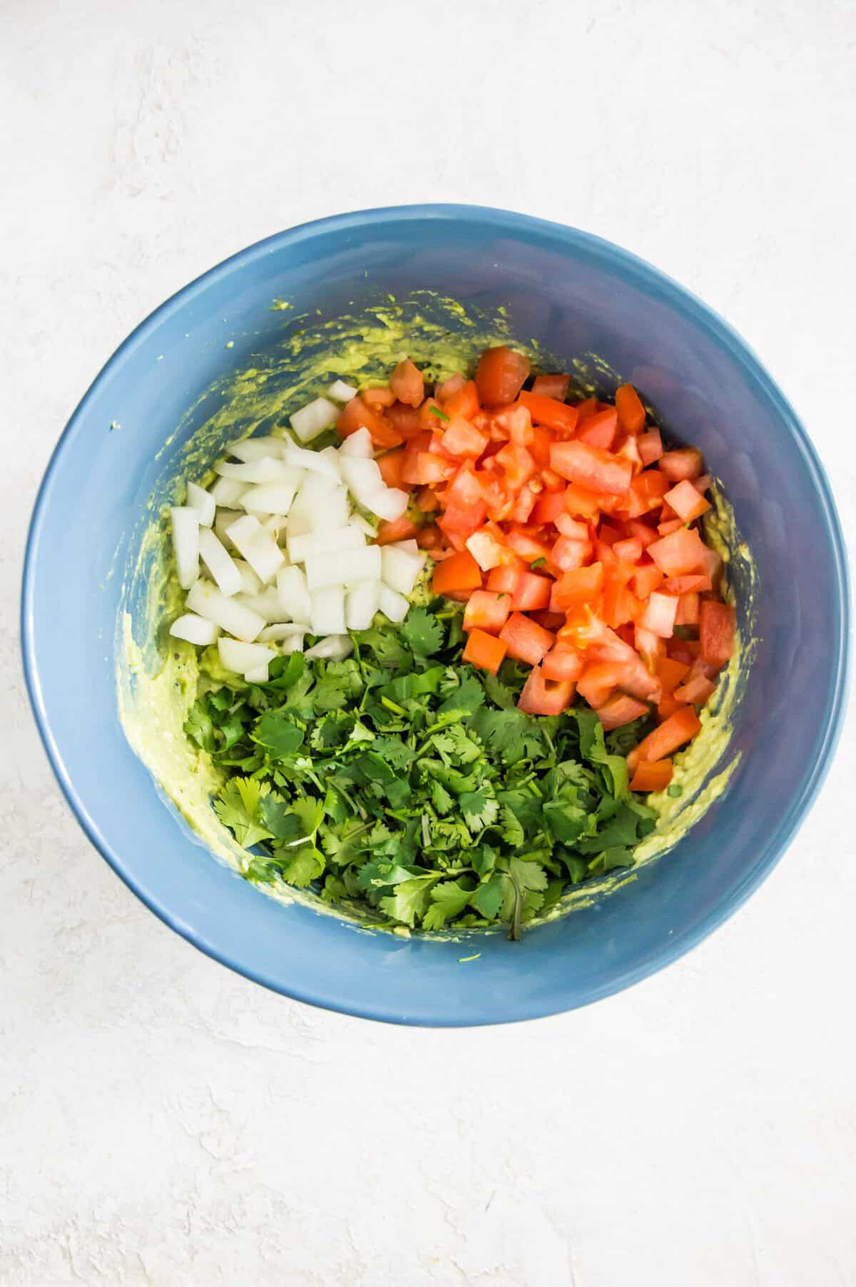 A bowl with chopped onion, tomato and cilantro in it.