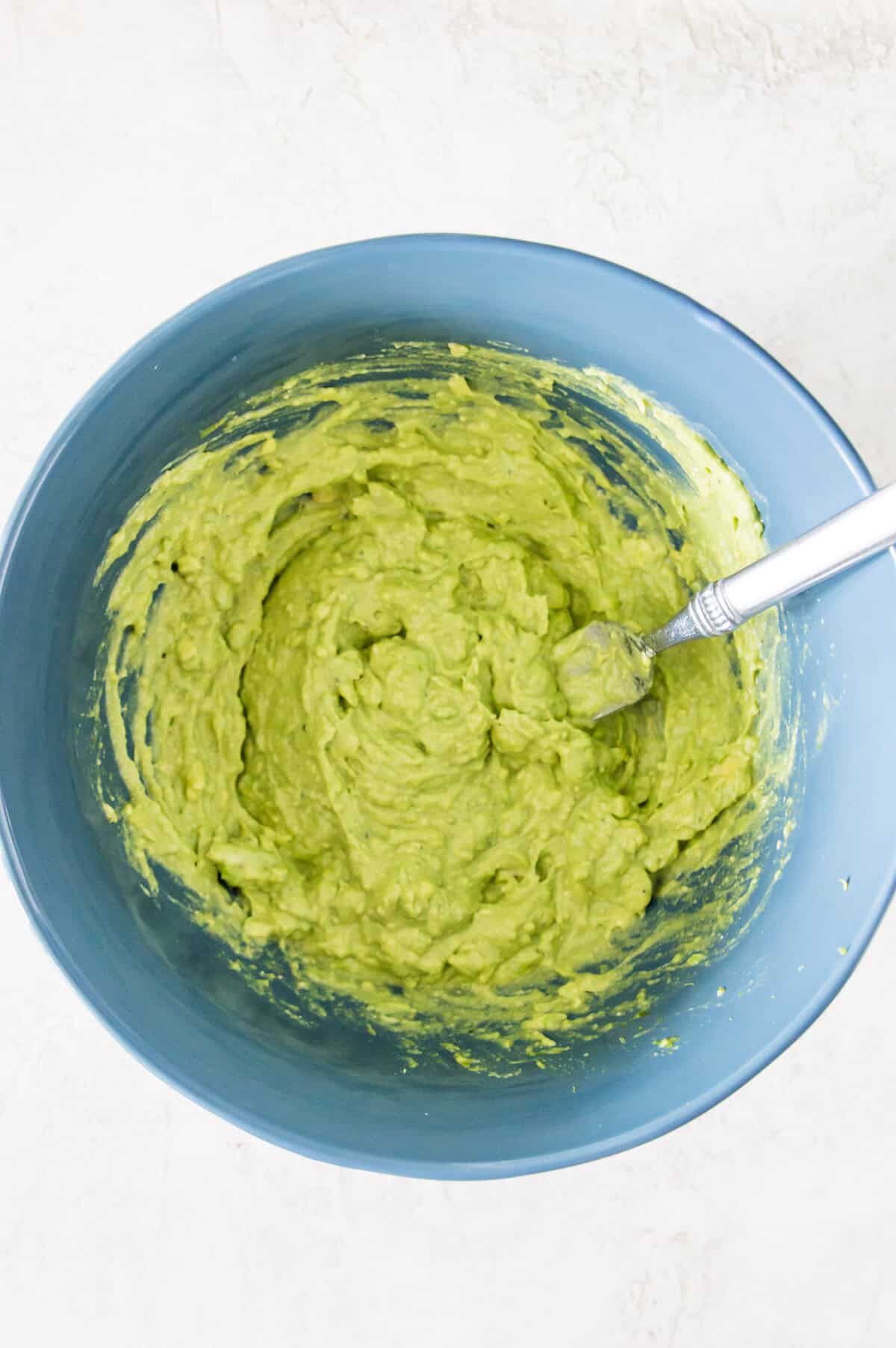A bowl with mashed avocado flesh in it.