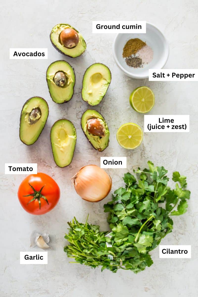 Avocados, cilantro, onion, tomato, garlic cloves and limes.