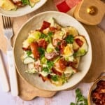 A bowl of potato salad garnished with fresh parsley and chopped green onion.
