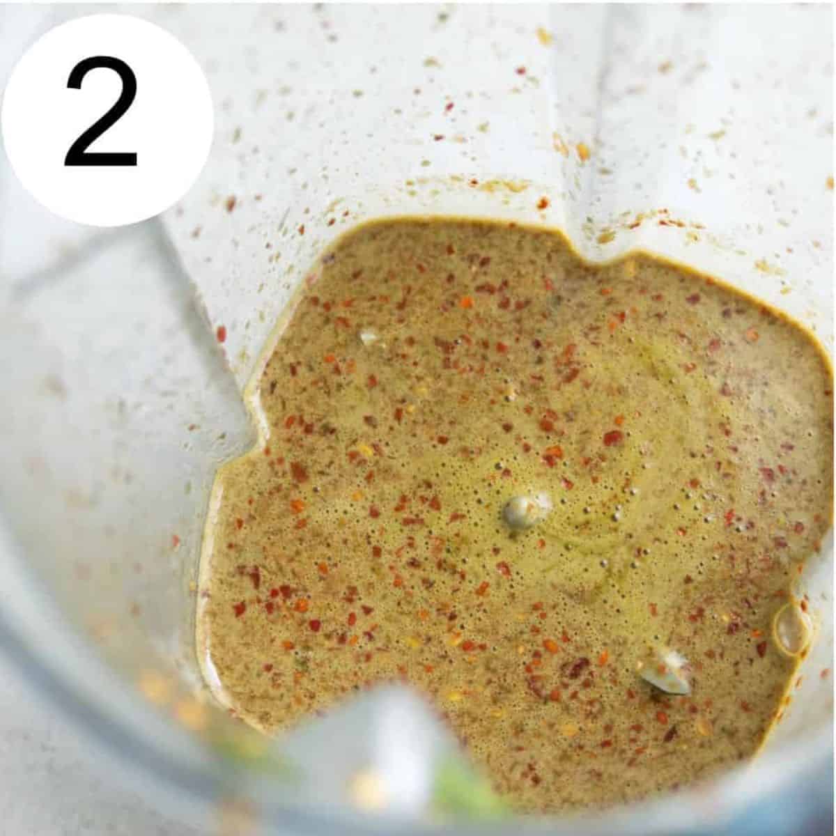 A blender with a creamy brown sauce in it.