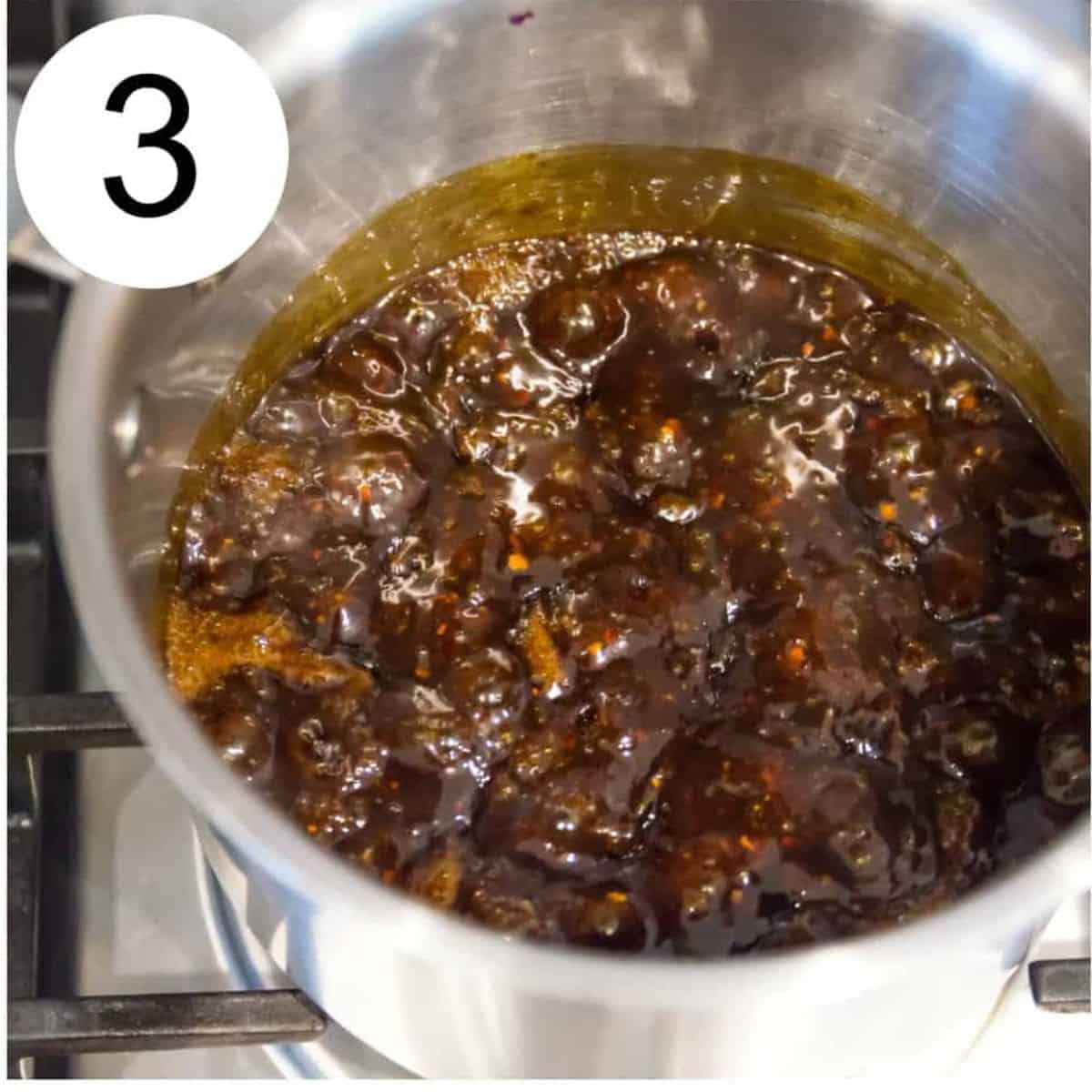 A saucepan with a brown sauce boiling in it.
