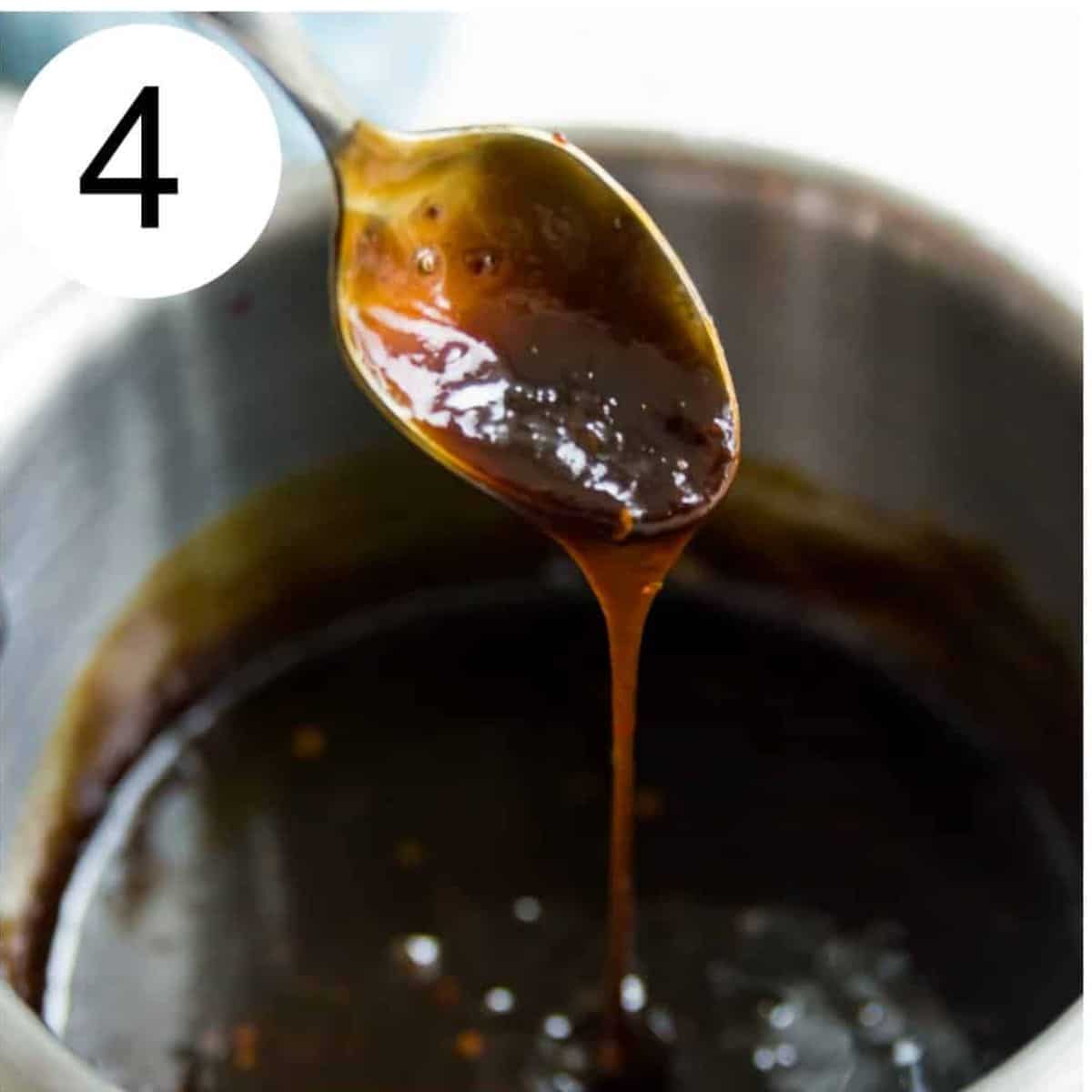 A spoon with a thick brown sauce dropping off of it.
