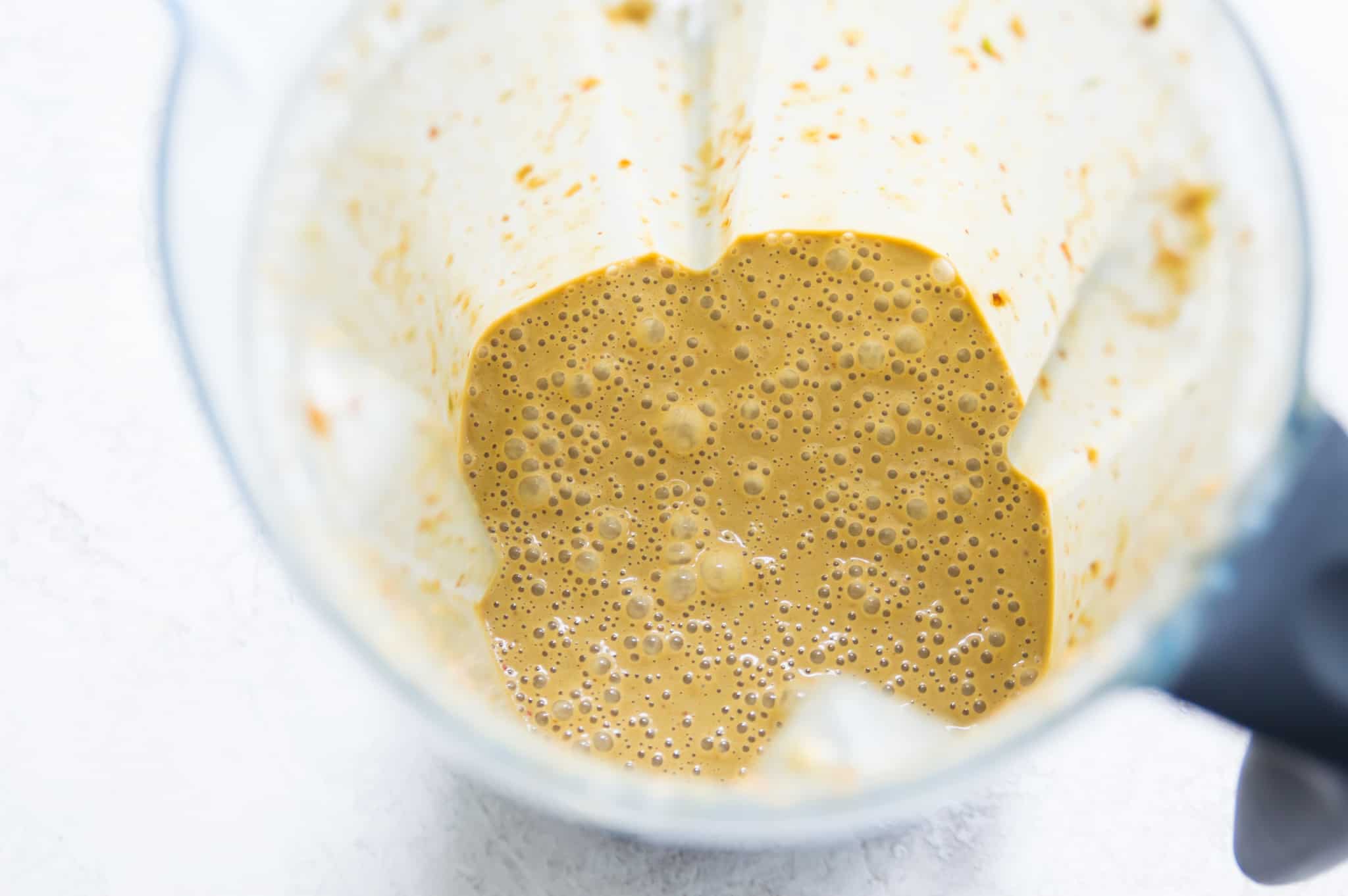 A blender with a brown creamy sauce in it.