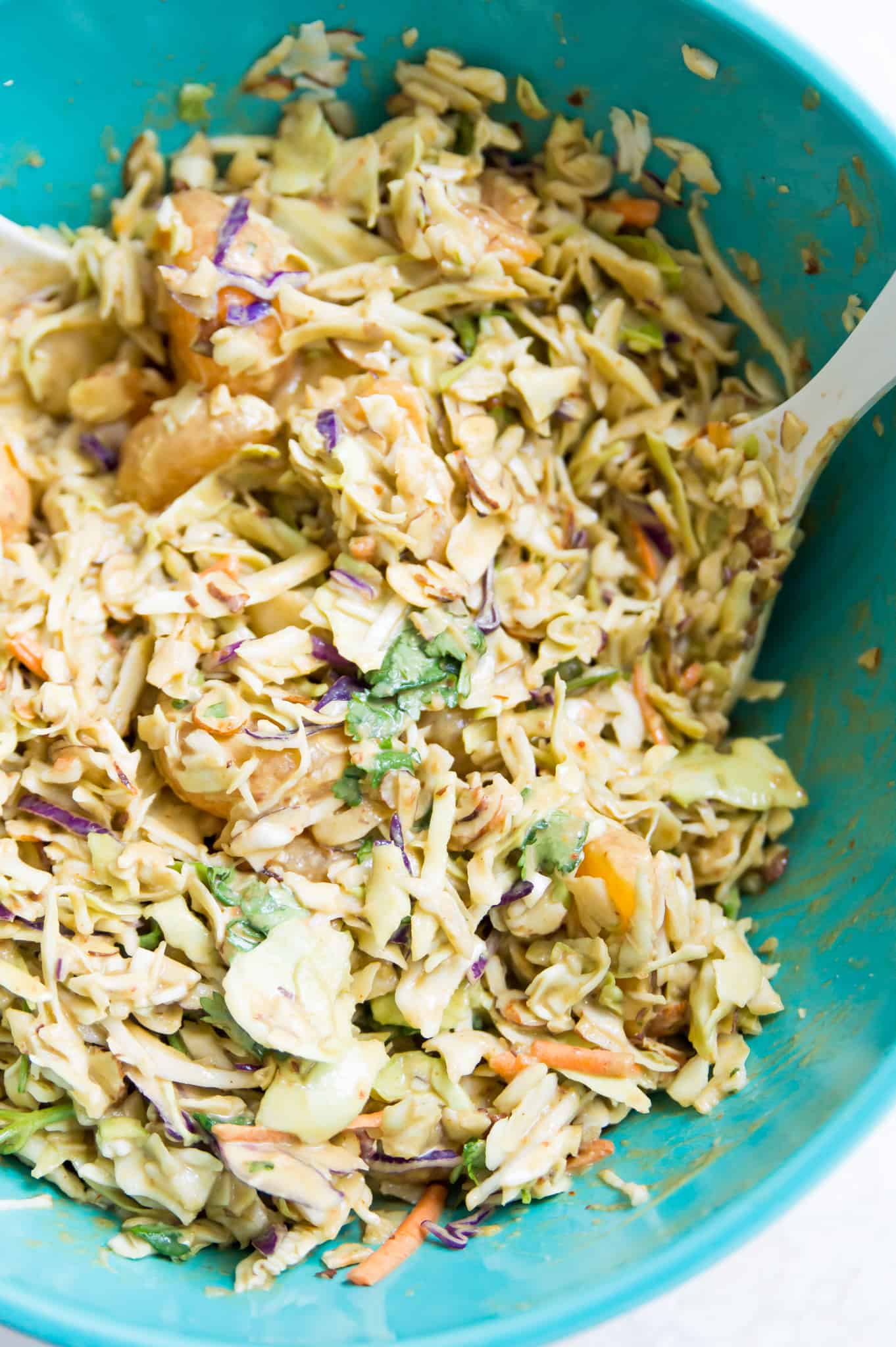 A bowl of coleslaw with a serving spoon in it.