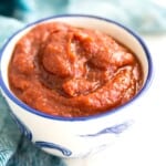 A bowl of bbq sauce with a blue tea towel around it.