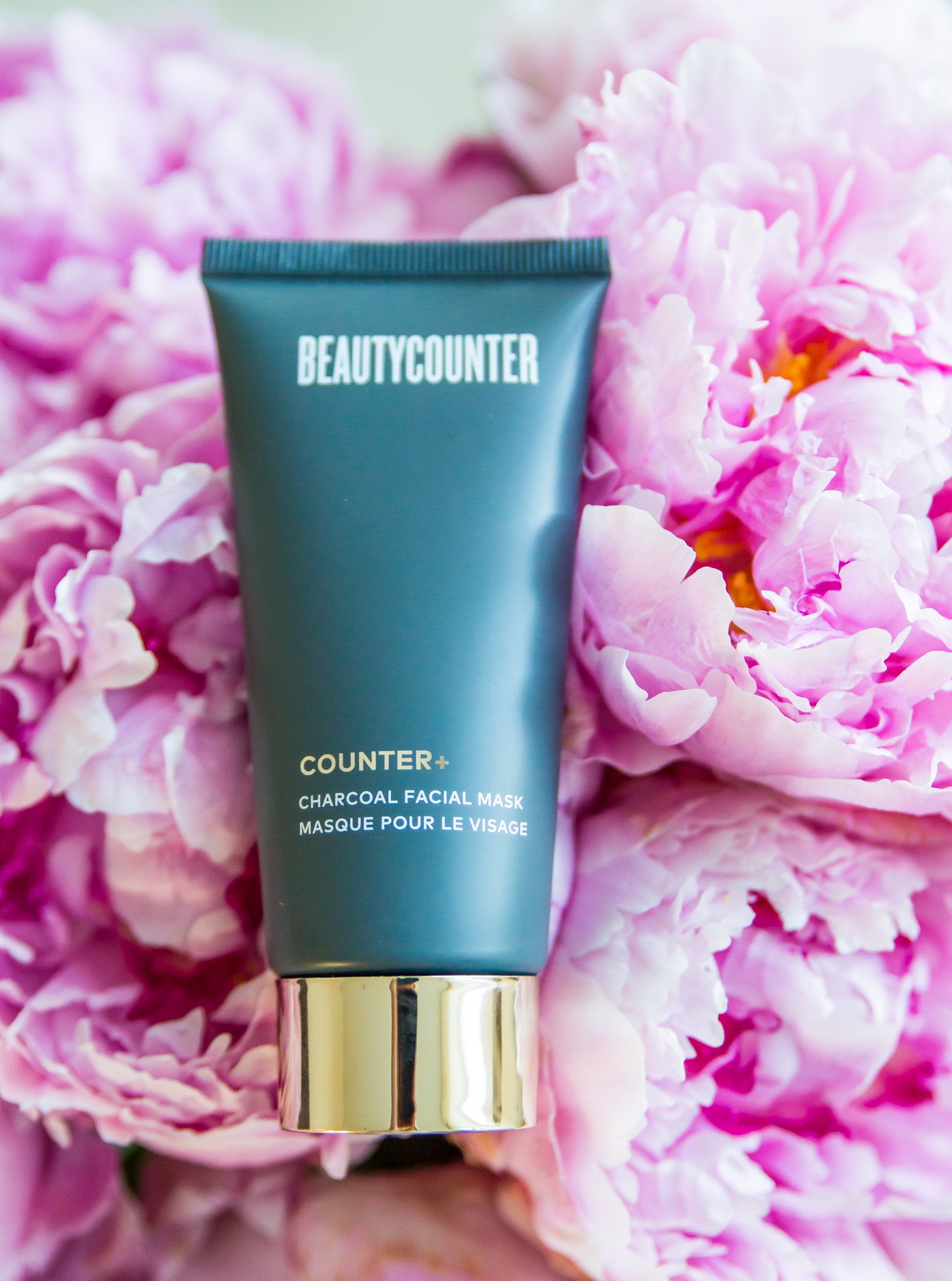 Beautycounter charcoal mask on top of pink peonies.