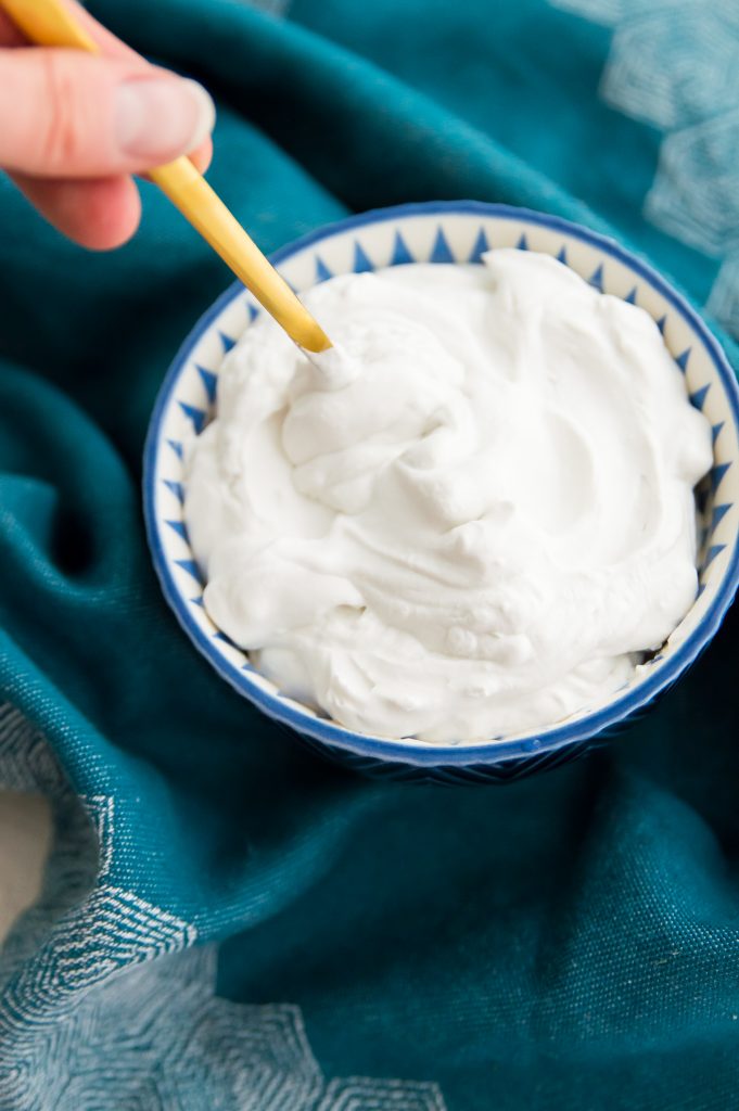 A bowl of coconut whipped cream with a gold spoon in it